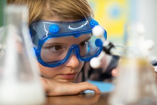 Closeup of student wearing goggles and examining a model